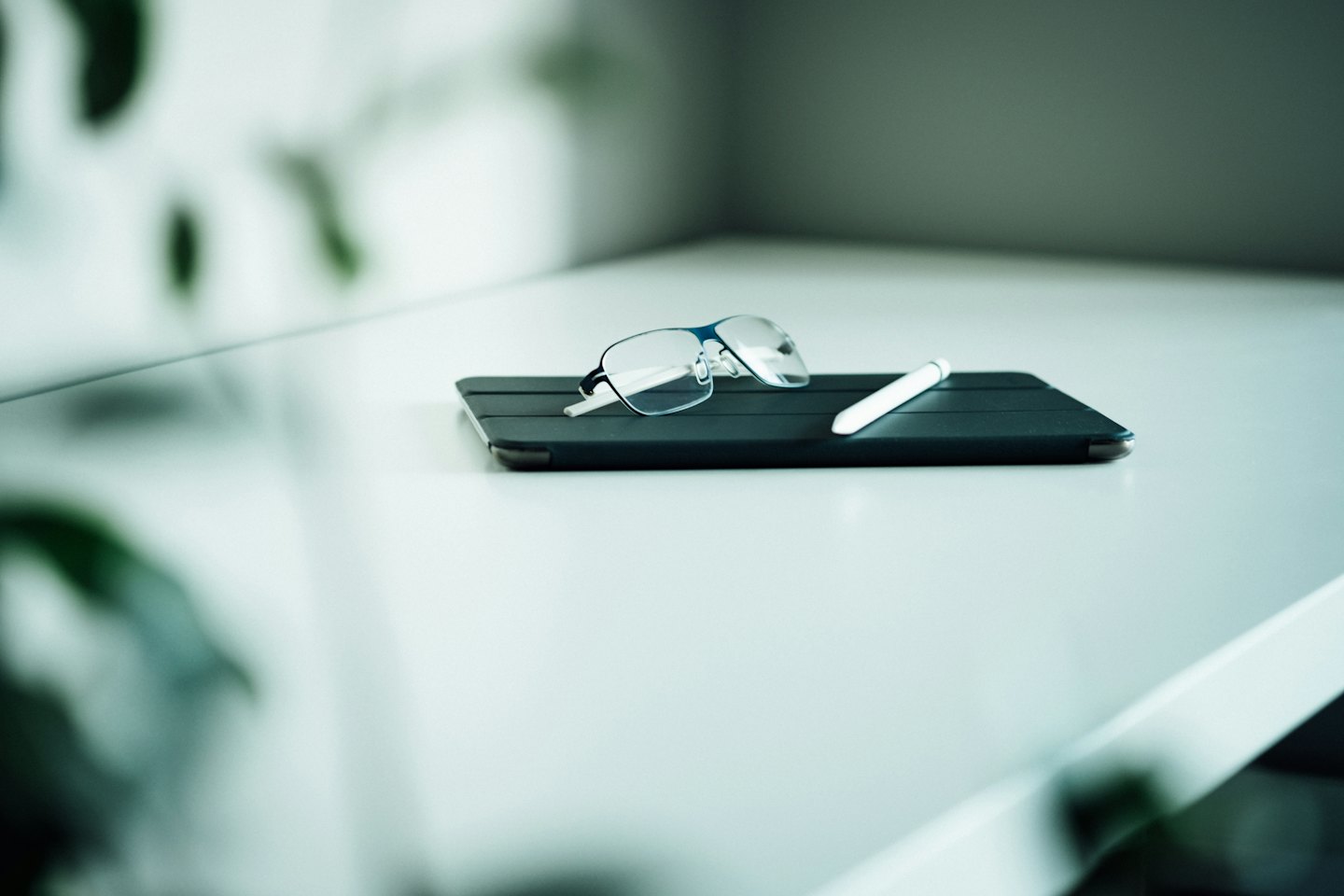 Modern glasses and stylus resting on a dark tablet.